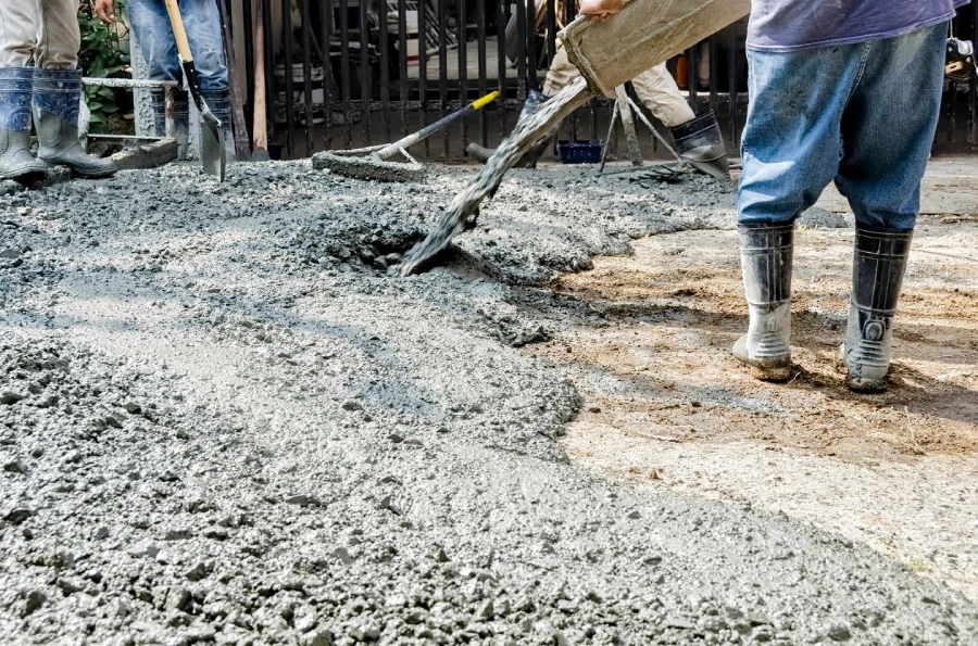 A person is pouring cement on the ground.