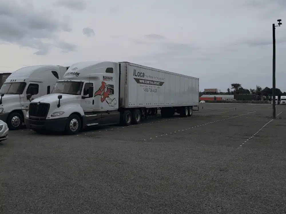 A white truck parked in the middle of an empty lot.