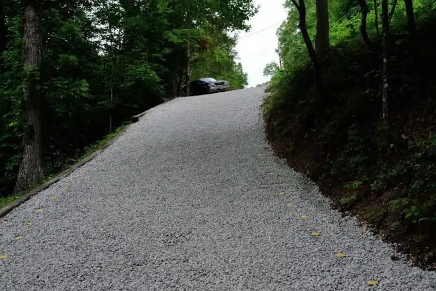 A car is driving down the road on gravel.